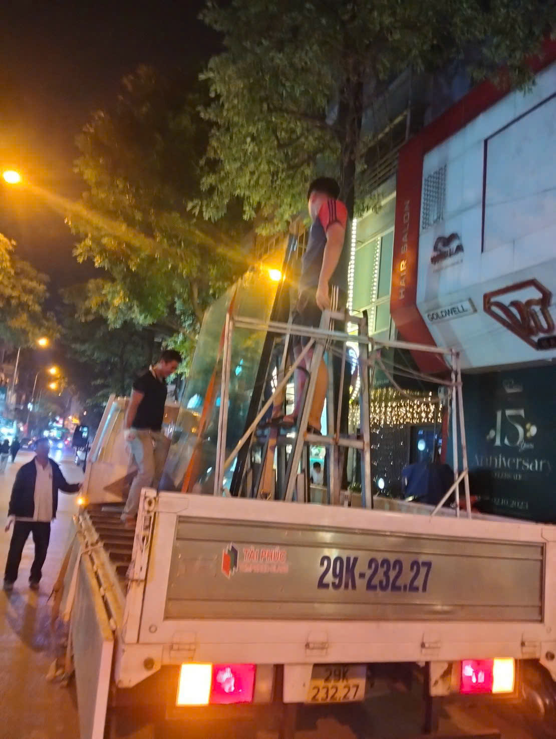 Đội thi công làm việc bên cạnh xe chở kính vào buổi tối